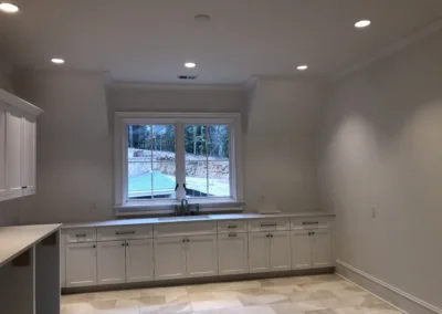 An empty kitchen with white cabinets and a sink.